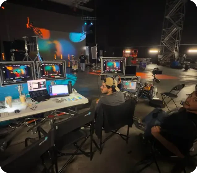 An event production desk with monitors facing a stage and display installation.