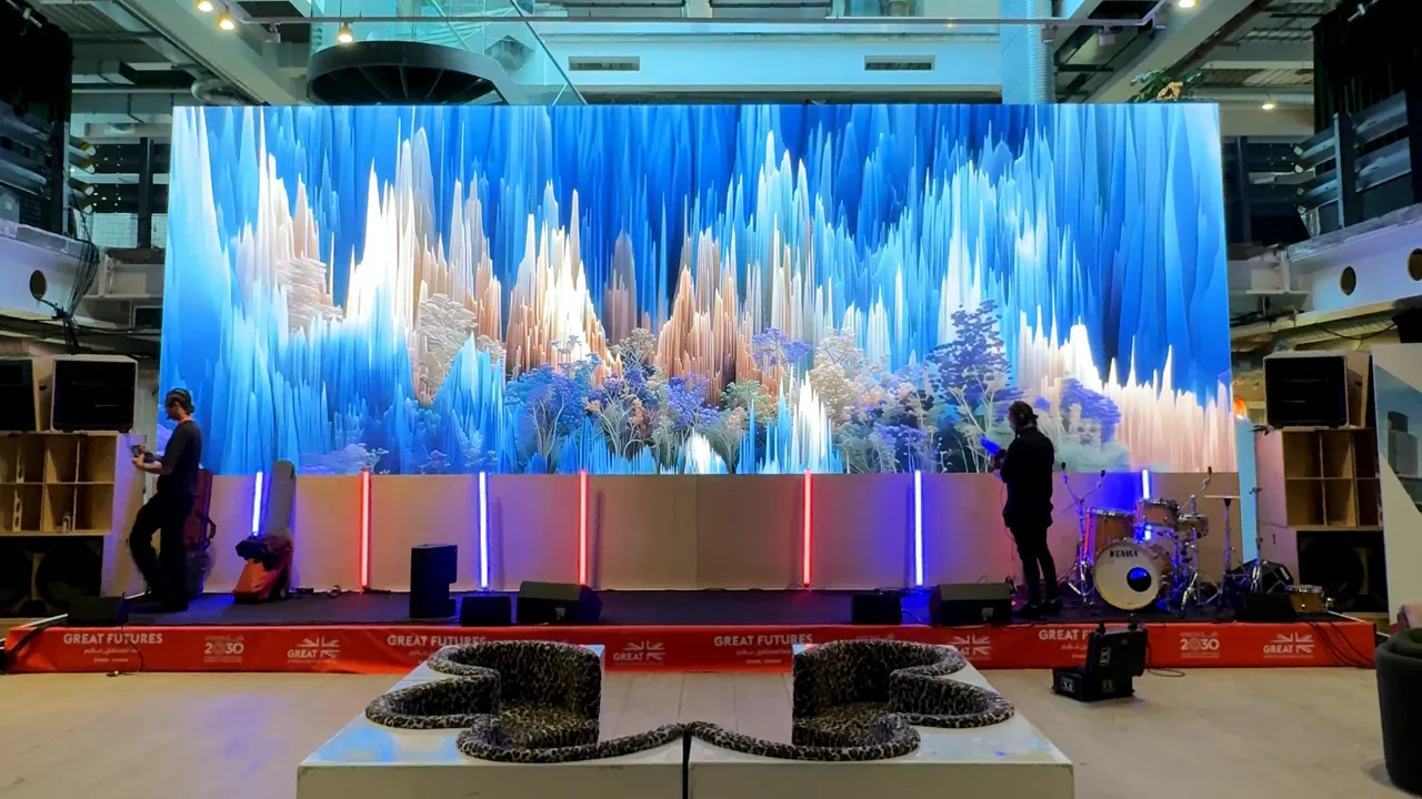 Phone footage of the GREAT FUTURES summit stage at 180 Studios: the film plays on a wide LED wall above the stage while crew work in front of it.