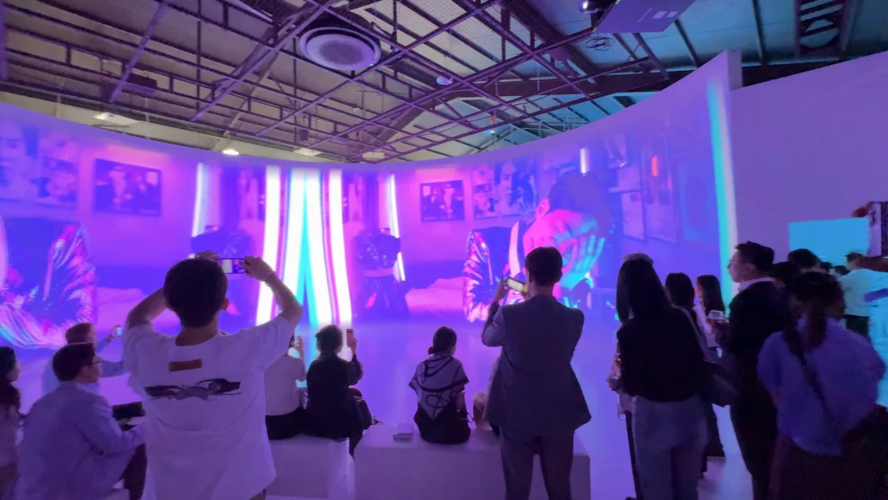Guests in silhouette filming 2AM on their phones as the film plays on a curved projection wall around them.